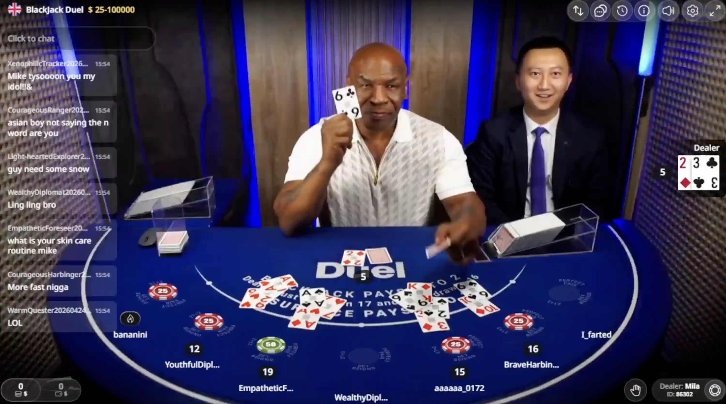 Mike Tyson live dealer at Duel Online Casino Blackjack Duel table holding the six of clubs on branded felt with $10 to $100,000 crypto limits and live chat overlay